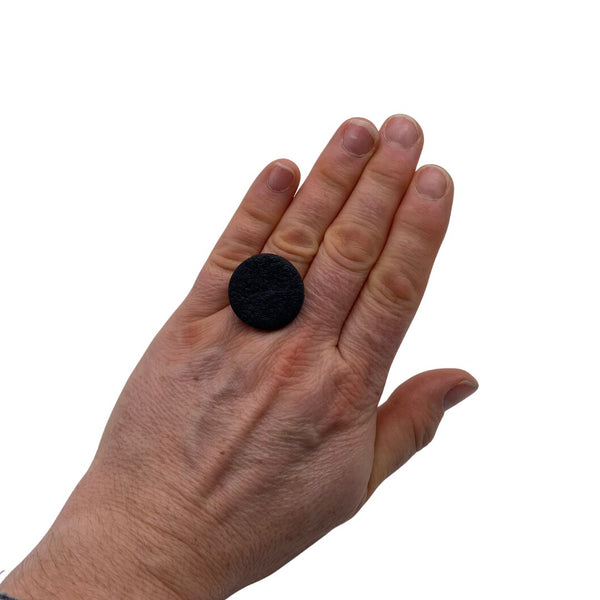 Someone wearing a Black small polymer clay ring on a white background