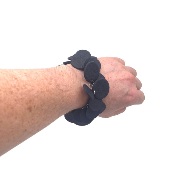 Someone's wrist when wearing a Black  polymer clay bracelet against a white background