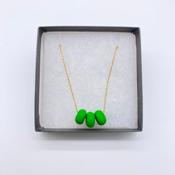 Bright Green polymer clay beads on a gold plated stainless steel chain in a box on a white background