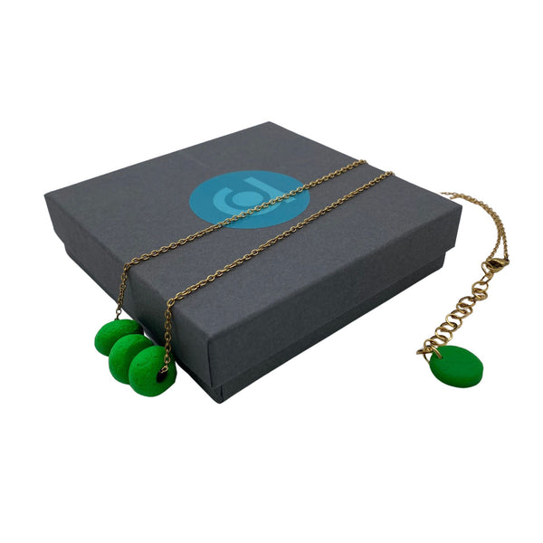 Bright Green polymer clay beads on a gold plated stainless steel chain on a box on a white background