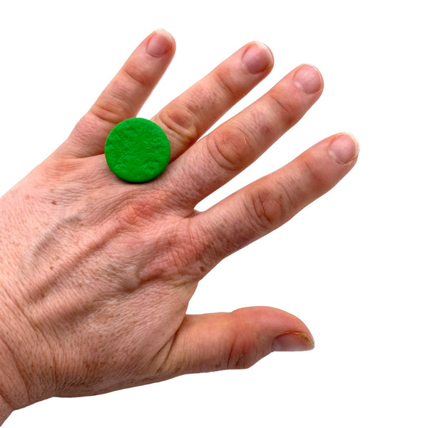 Someone wearing a Bright Green small polymer clay ring on a white background