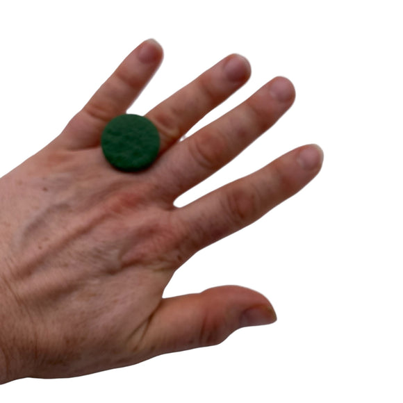 Someone wearing a Dark Green small polymer clay ring on a white background