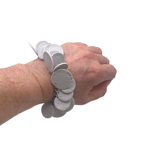 Someone's wrist wearing a Grey polymer clay bracelet on white background