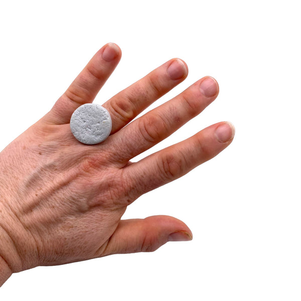 Someone wearing a Grey small polymer clay ring on a white background