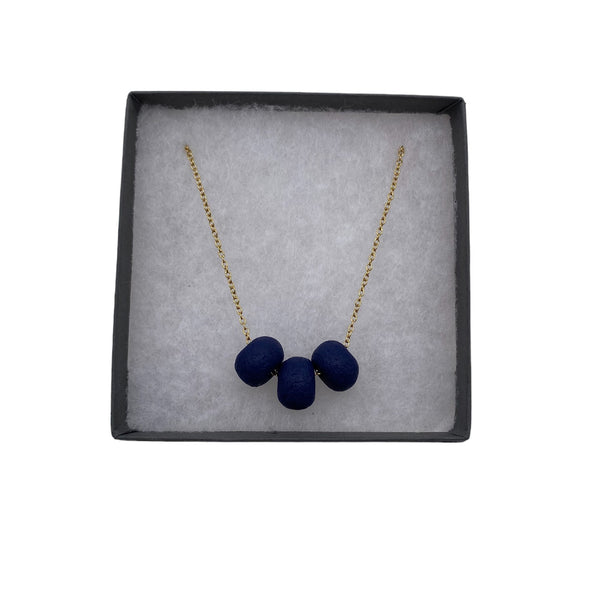 Navy Blue polymer clay beads on a gold plated stainless steel chain in a a box on a white background