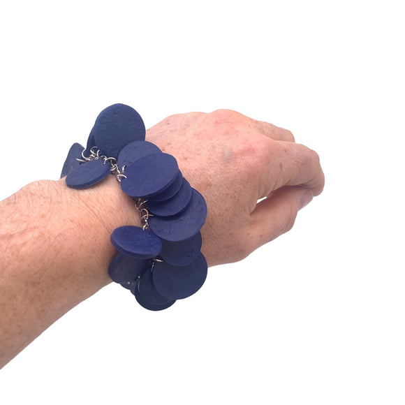 Someone's wrist wearing  Navy Blue polymer clay bracelet on white background