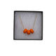 Orange polymer clay beads on a gold plated stainless steel chain in a box on a white background