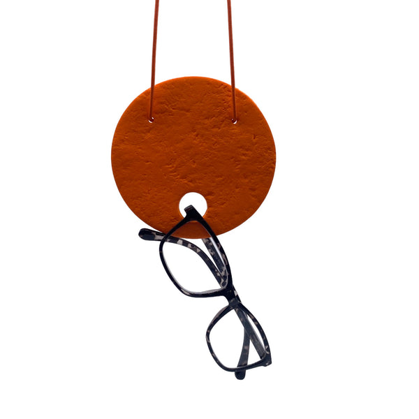 Large Orange Polymer Clay Statement necklace holding sunglasses on a white background