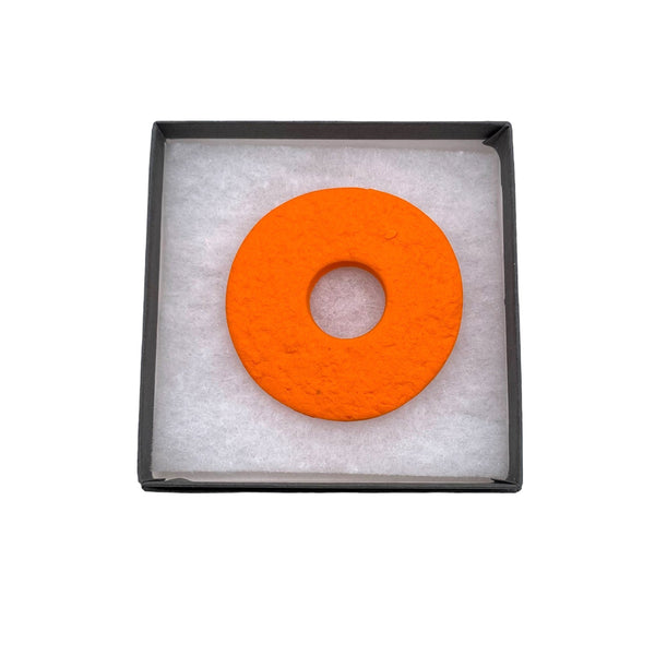 Orange polymer clay brooch in a box on a white background