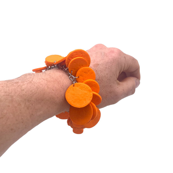 Someone's wrist wearing an Orange polymer clay bracelet on white background