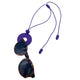 Purple Polymer clay necklace and glasses holder holding sunglasses on a white background