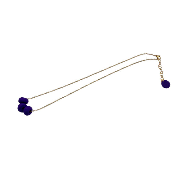 Purple polymer clay beads on a gold plated stainless steel chain on a white background