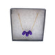 Purple polymer clay beads on a gold plated stainless steel chain in a box on a white background