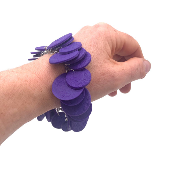 Someone's wrist wearing a Purple polymer clay bracelet on white background