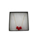 Red polymer clay beads on a gold plated stainless steel chain in a box on a white background