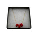 Red polymer clay beads on a gold plated stainless steel chain in a box on a white background