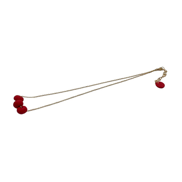 Red polymer clay beads on a gold plated stainless steel chain on a white background