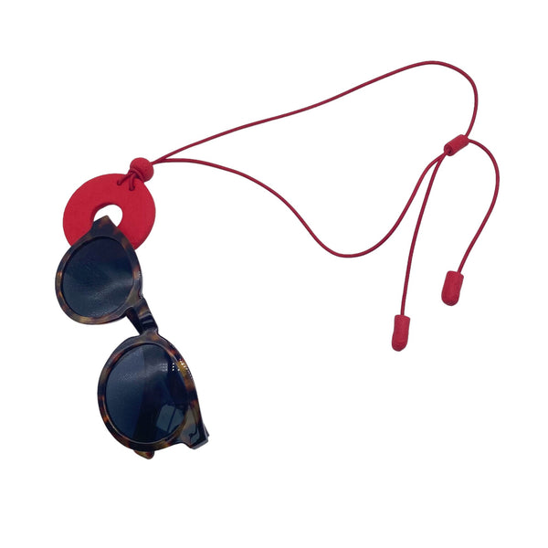 Red Polymer clay necklace and glasses holder holding sunglasses on a white background