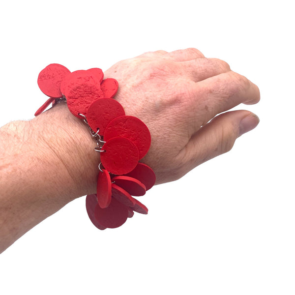 Someone's wrist wearing a Red polymer clay bracelet on white background