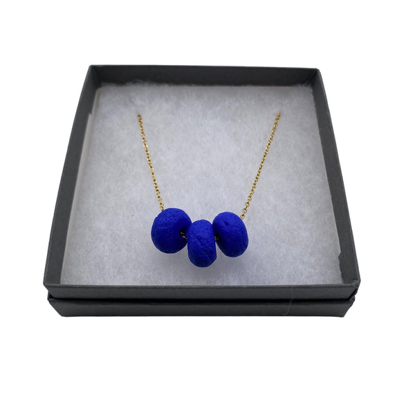 Royal Blue polymer clay beads on a gold plated stainless steel chain on a white background