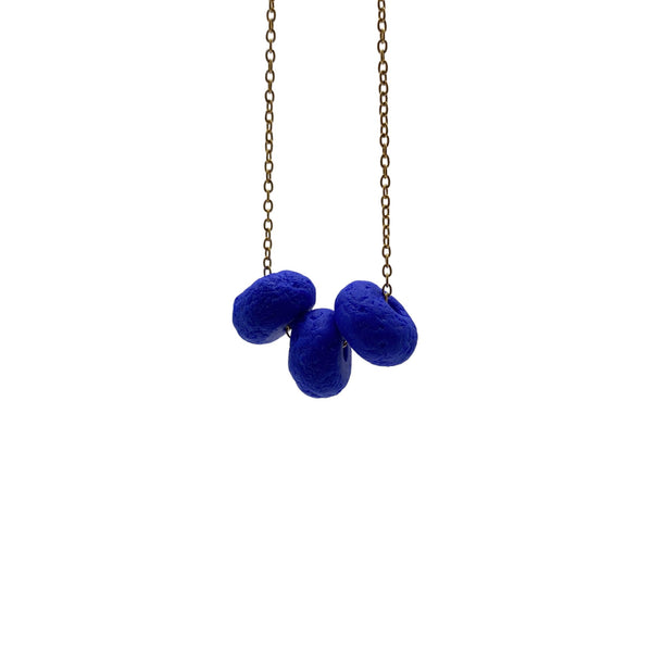 Royal Blue polymer clay beads on a gold plated stainless steel chain on a white background