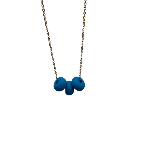 Turquoise polymer clay beads on a gold plated stainless steel chain on a white background