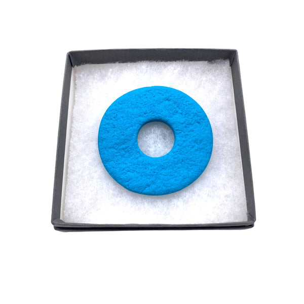 Turquoise polymer clay brooch in a box on a white background