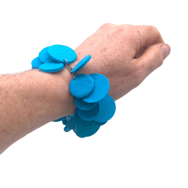 Someone's wrist wearing a Turquoise polymer clay bracelet on white background