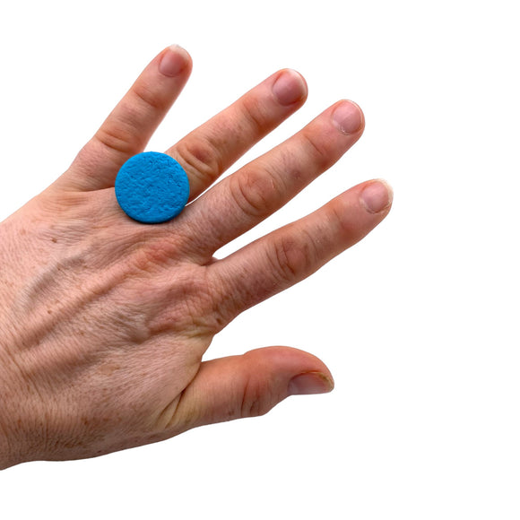 Someone wearing a Turquoise small polymer clay ring on a white background