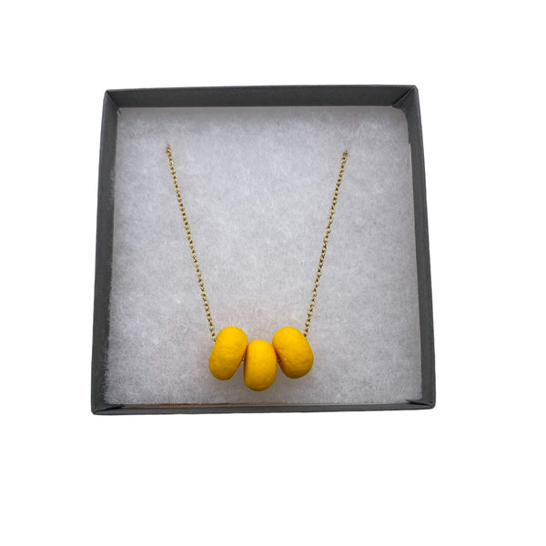 Yellow polymer clay beads on a gold plated stainless steel chain in a box on a white background