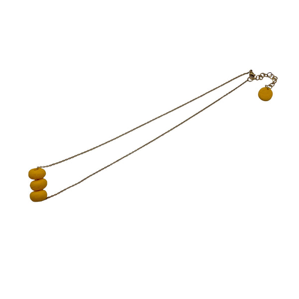 Yellow polymer clay beads on a gold plated stainless steel chain on a white background