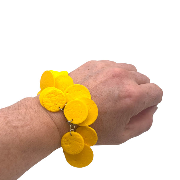 Someone's wrist wearing a Yellow polymer clay bracelet on white background