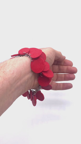 Video of someone's wrist wearing a Red polymer clay bracelet on white background