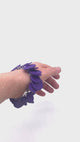 Someone's wrist wearing a Purple polymer clay bracelet on white background