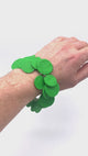 Video of someone's wrist wearing a Bright Green polymer bracelet on a white background 