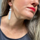 Someone wearing Grey Polymer Clay Dangle earrings with shepherd hooks. 