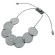 grey polymer clay statement necklace with overlapping discs on elastic cord shown on a small grey block