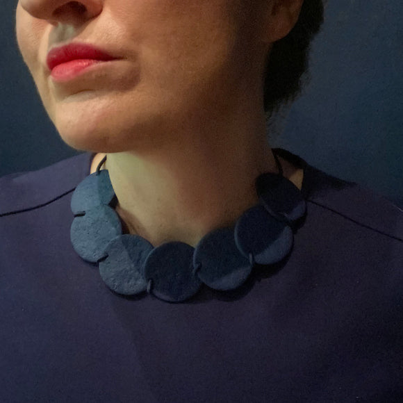 Someone wearing a Navy blue polymer clay statement necklace with overlapping discs on an elastic cord