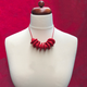 Red Disc and Bead Polymer Clay statement necklace with coordinating elastic cord on a mannequin to show the various lengths it can be worn