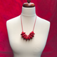 Red Disc and Bead Polymer Clay statement necklace with coordinating elastic cord on a mannequin to show the various lengths it can be worn