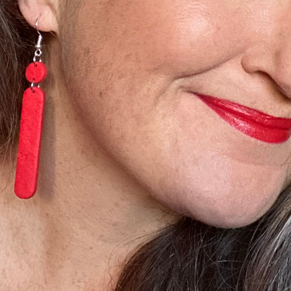 Someone wearing Red Polymer Clay Dangle earrings with shepherd hooks. 