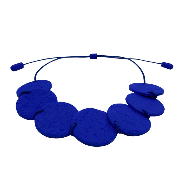 Royal blue polymer clay statement necklace with overlapping discs on an elastic cord - image at an angle