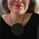 Someone wearing black disc polymer clay statement necklace with coordinating black cord