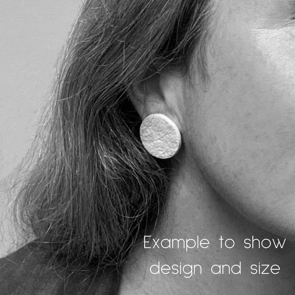 Showing someone wearing polymer clay round stud earrings. Image in black and white to show the design and size of earrings