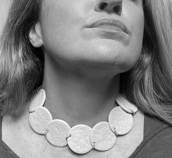 Someone wearing a Polymer Clay statement necklace with overlapping discs. Image is black and white.