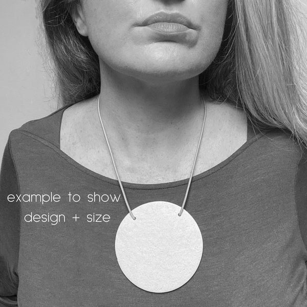 Someone wearing disc polymer clay statement necklace with coordinating  cord. Image is in black and white to show design and size. 