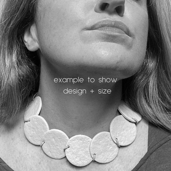 Someone wearing a polymer clay statement necklace with overlapping discs on an elastic cord. Image is in black and white.